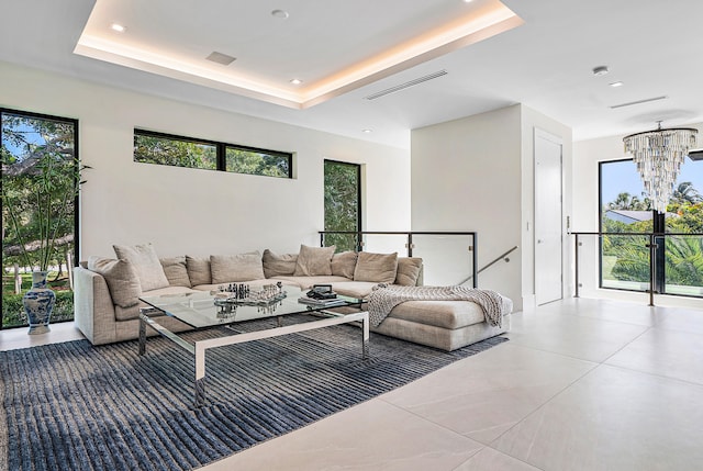 living room with tile flooring, a chandelier, and a raised ceiling