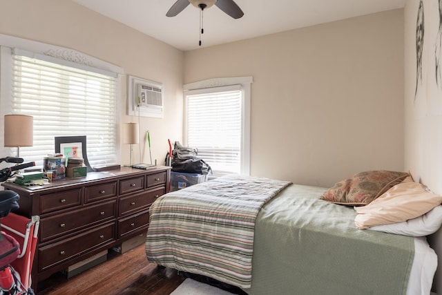 bedroom with a wall mounted air conditioner, dark hardwood / wood-style flooring, ceiling fan, and multiple windows