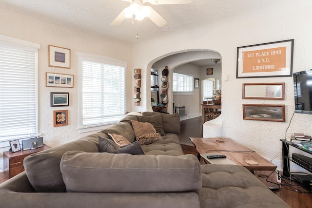 living room with a textured ceiling, wood-type flooring, ceiling fan, and plenty of natural light