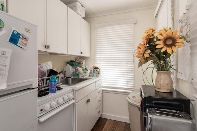 kitchen with white appliances, dark wood-type flooring, white cabinetry, ornamental molding, and sink