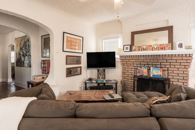 living room featuring wood-type flooring, a fireplace, and a textured ceiling