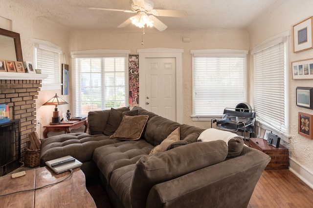 living room featuring a fireplace, hardwood / wood-style floors, ceiling fan, and a textured ceiling