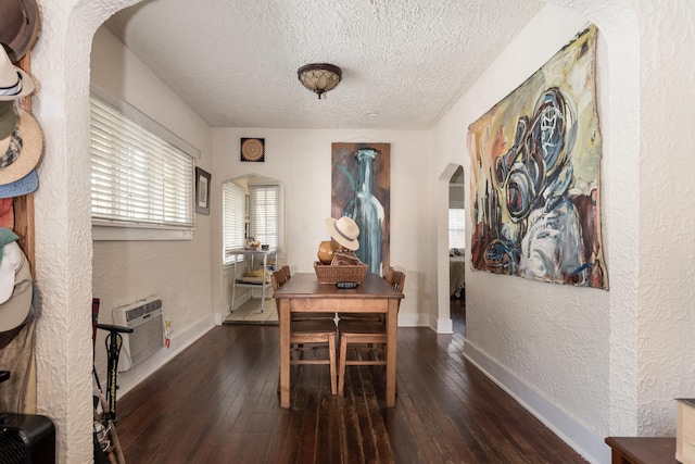 dining space with an AC wall unit, dark hardwood / wood-style floors, and a textured ceiling