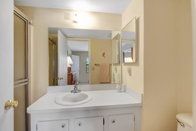 bathroom with vanity, a shower with shower door, and toilet