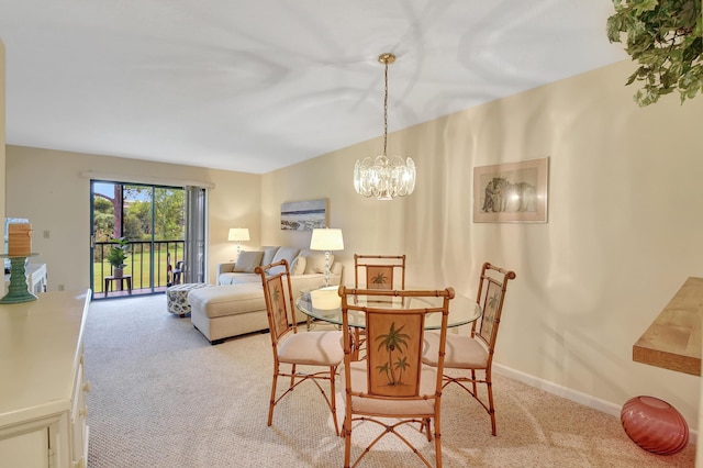 dining space featuring light carpet and an inviting chandelier