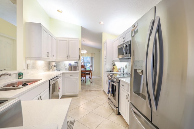 kitchen with stainless steel appliances, vaulted ceiling, sink, and white cabinetry