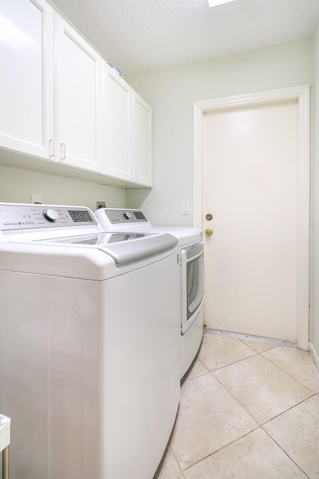 laundry room with cabinets, independent washer and dryer, and light tile floors