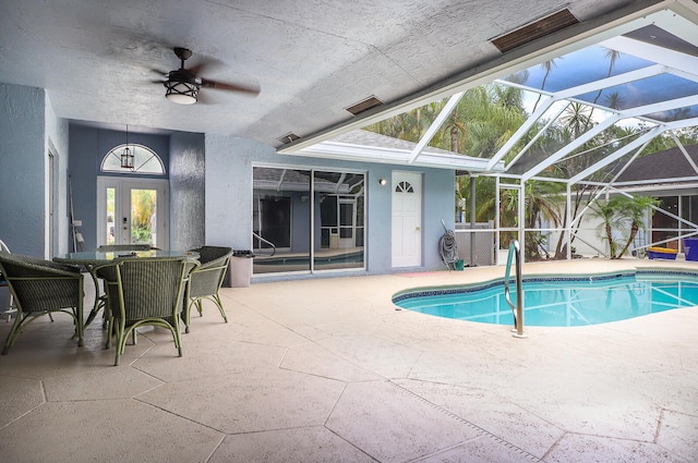 view of pool with a patio area, glass enclosure, and ceiling fan