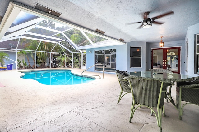 view of swimming pool featuring ceiling fan, glass enclosure, and a patio area