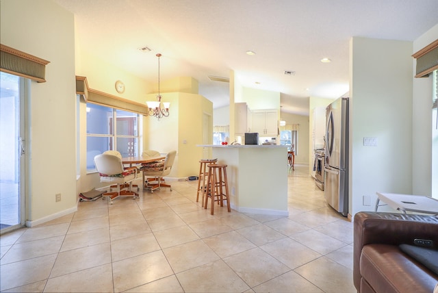 kitchen with stainless steel fridge, a breakfast bar area, light tile floors, hanging light fixtures, and a wealth of natural light