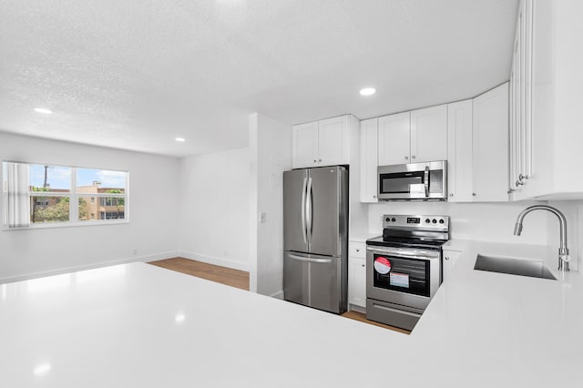 kitchen with white cabinets, a textured ceiling, stainless steel appliances, and sink