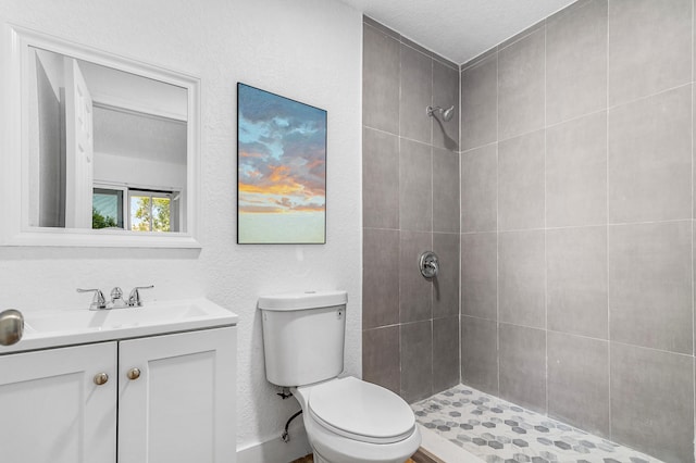 bathroom with a tile shower, vanity, a textured ceiling, and toilet