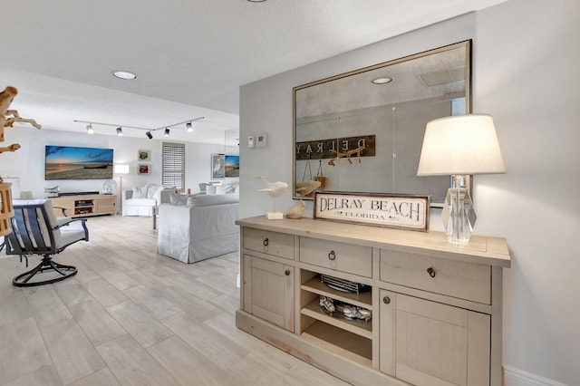 interior space featuring a textured ceiling, light wood-type flooring, and rail lighting