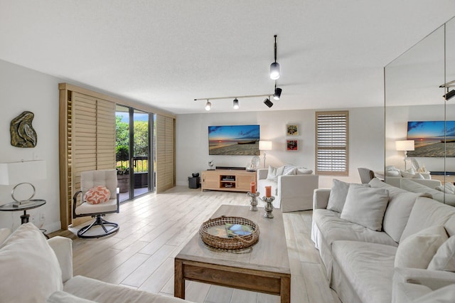 living room with light hardwood / wood-style flooring, a textured ceiling, and rail lighting