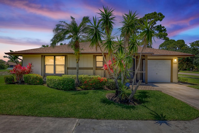 single story home featuring a garage and a lawn