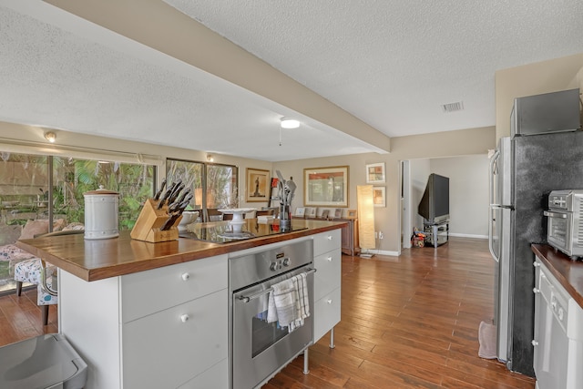 kitchen featuring butcher block countertops, stainless steel appliances, dark hardwood / wood-style floors, and a wealth of natural light