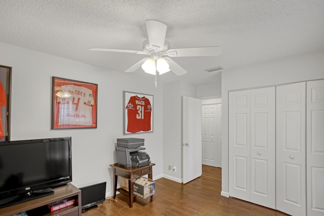 misc room with a textured ceiling, wood-type flooring, and ceiling fan