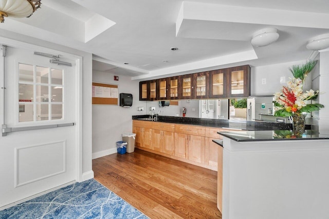 kitchen with a tray ceiling, hardwood / wood-style flooring, kitchen peninsula, and light brown cabinets