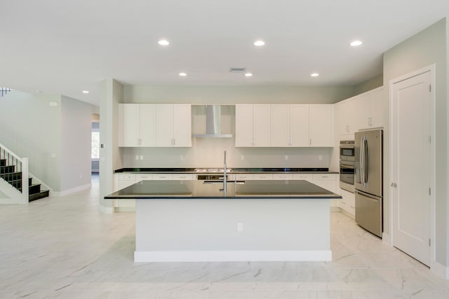 kitchen featuring an island with sink, wall chimney range hood, sink, white cabinets, and stainless steel fridge with ice dispenser