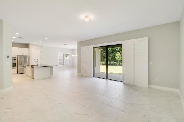 empty room with sink, a wealth of natural light, and light tile floors