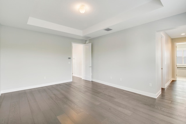 unfurnished room with a tray ceiling and hardwood / wood-style floors