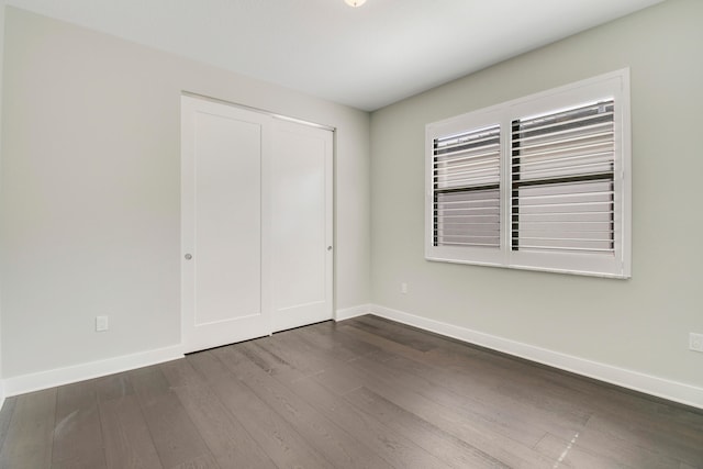 unfurnished bedroom with a closet and dark hardwood / wood-style flooring