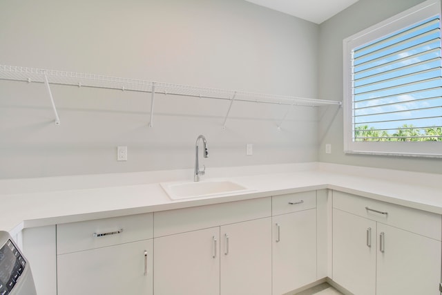 clothes washing area with sink and cabinets