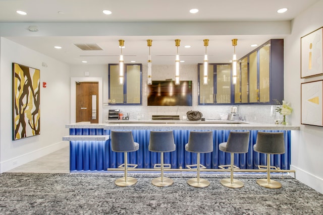 kitchen with decorative light fixtures, backsplash, and a breakfast bar area