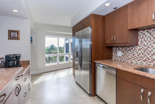 kitchen featuring tasteful backsplash, appliances with stainless steel finishes, light tile floors, and light stone counters