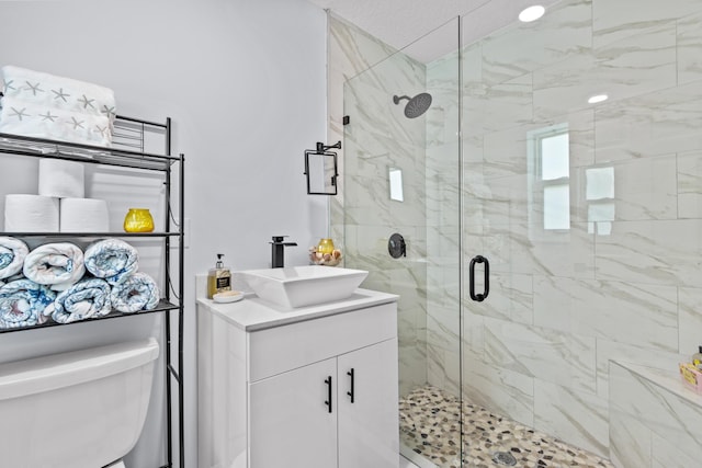 bathroom featuring a shower with shower door, toilet, and vanity