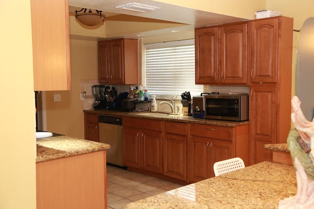 kitchen with light tile flooring, backsplash, light stone countertops, appliances with stainless steel finishes, and sink