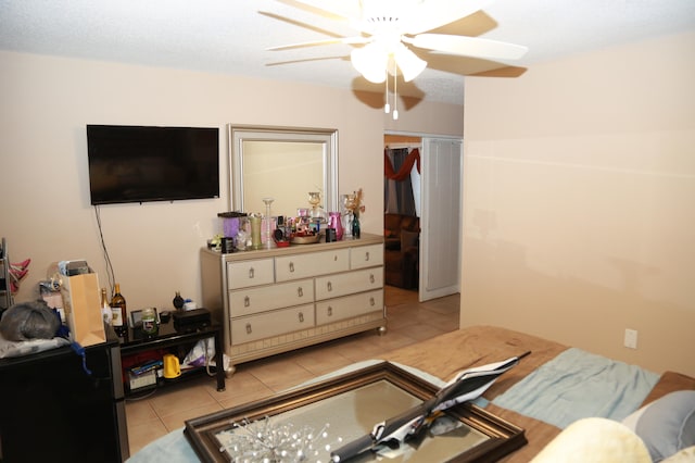 bedroom with ceiling fan, a closet, a textured ceiling, and light tile flooring