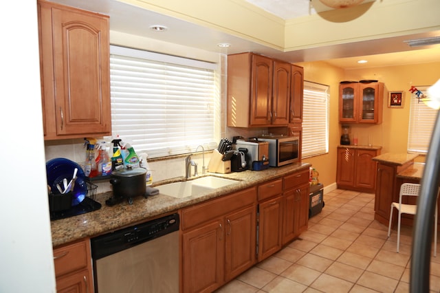 kitchen featuring light stone countertops, backsplash, light tile floors, sink, and appliances with stainless steel finishes