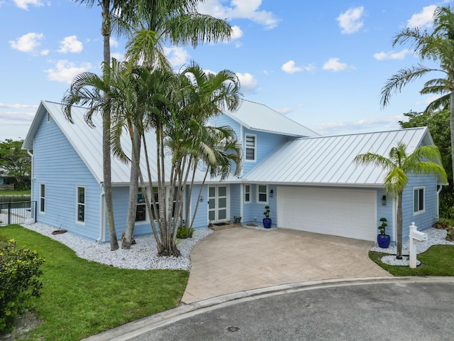9029 SE Breeze Way, Hobe Sound, FL 33455 - view of front of home featuring fence, an attached garage, metal roof, a front lawn, and decorative driveway
