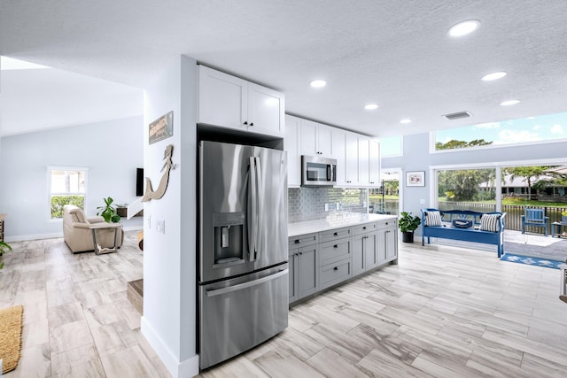 kitchen with gray cabinets, white cabinetry, stainless steel appliances, and a wealth of natural light