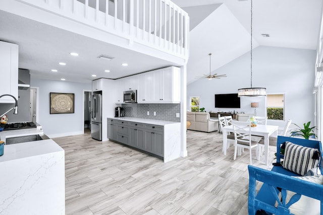 kitchen featuring light stone countertops, ceiling fan, stainless steel appliances, white cabinets, and high vaulted ceiling