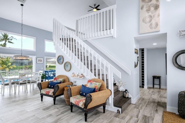 stairway featuring wood-type flooring, a towering ceiling, and ceiling fan