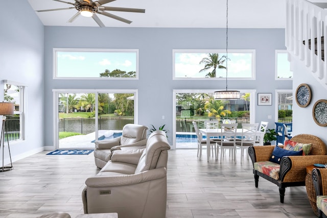 living room featuring light hardwood / wood-style flooring, a high ceiling, and ceiling fan