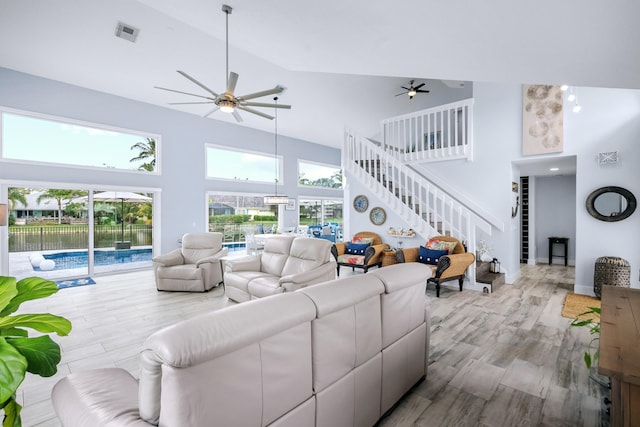 living room featuring light hardwood / wood-style floors, high vaulted ceiling, and ceiling fan