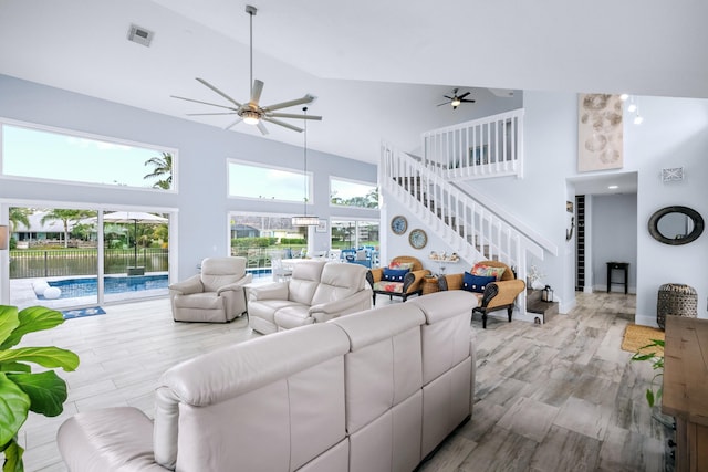 9029 SE Breeze Way, Hobe Sound, FL 33455 - living area featuring wood finished floors, a ceiling fan, high vaulted ceiling, visible vents, and stairs
