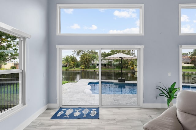 doorway to outside featuring a wealth of natural light, light hardwood / wood-style flooring, and a water view