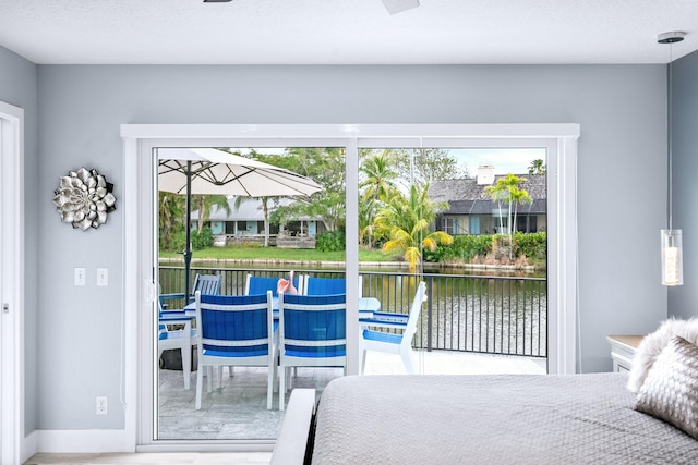 9029 SE Breeze Way, Hobe Sound, FL 33455 - bedroom with wood finished floors, a water view, baseboards, and access to exterior