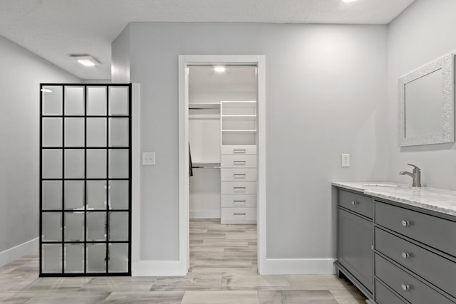 9029 SE Breeze Way, Hobe Sound, FL 33455 - full bathroom with wood finished floors, baseboards, walk in shower, vanity, and a spacious closet
