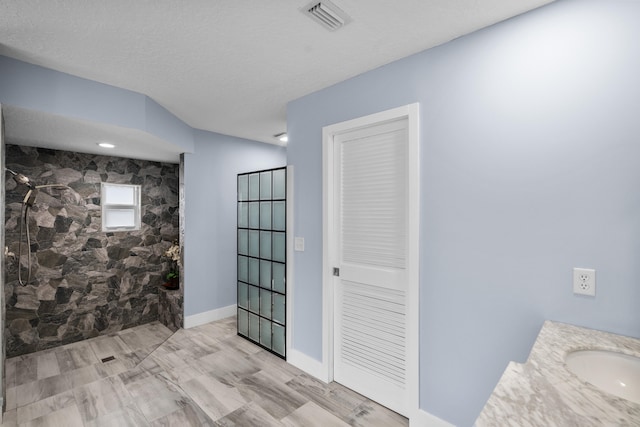 bathroom with vanity, a textured ceiling, and walk in shower