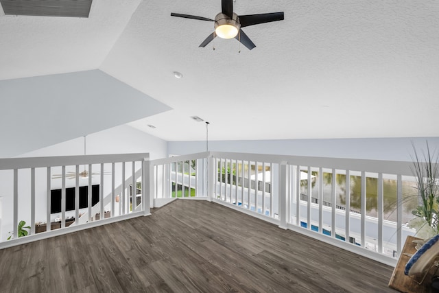 interior space with dark wood-type flooring, ceiling fan, a textured ceiling, and vaulted ceiling