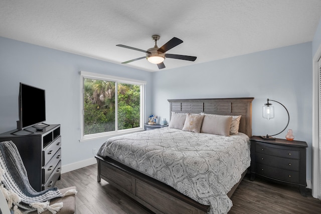 bedroom with dark wood-type flooring, ceiling fan, and a textured ceiling