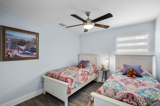 bedroom featuring dark wood-type flooring, ceiling fan, and a textured ceiling