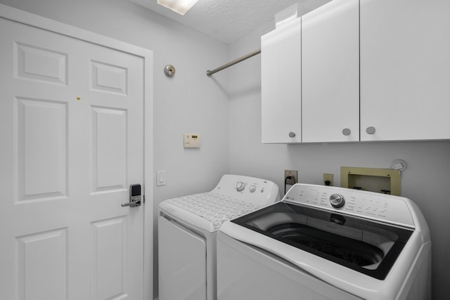 laundry room featuring cabinets, a textured ceiling, and washing machine and clothes dryer