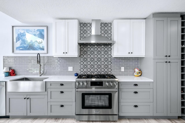 kitchen featuring tasteful backsplash, appliances with stainless steel finishes, a textured ceiling, light hardwood / wood-style floors, and wall chimney exhaust hood