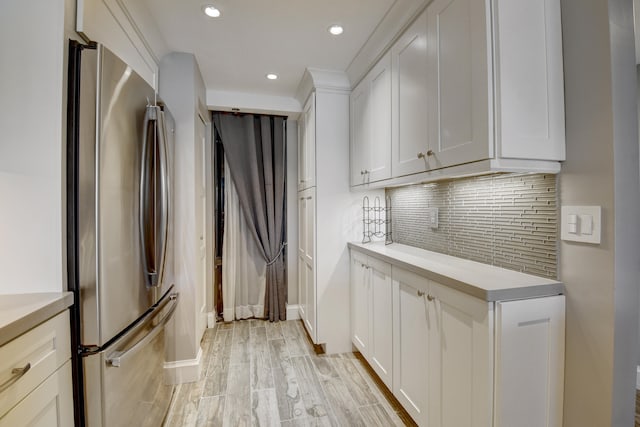 kitchen featuring stainless steel refrigerator, tasteful backsplash, light hardwood / wood-style flooring, and white cabinets